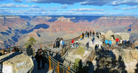 People taking in the view of Grand Canyon from the guardrail. 