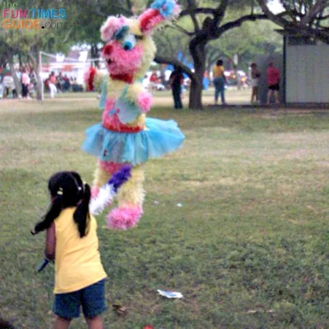 Little girl at Easter picnic hitting the Easter bunny pinata